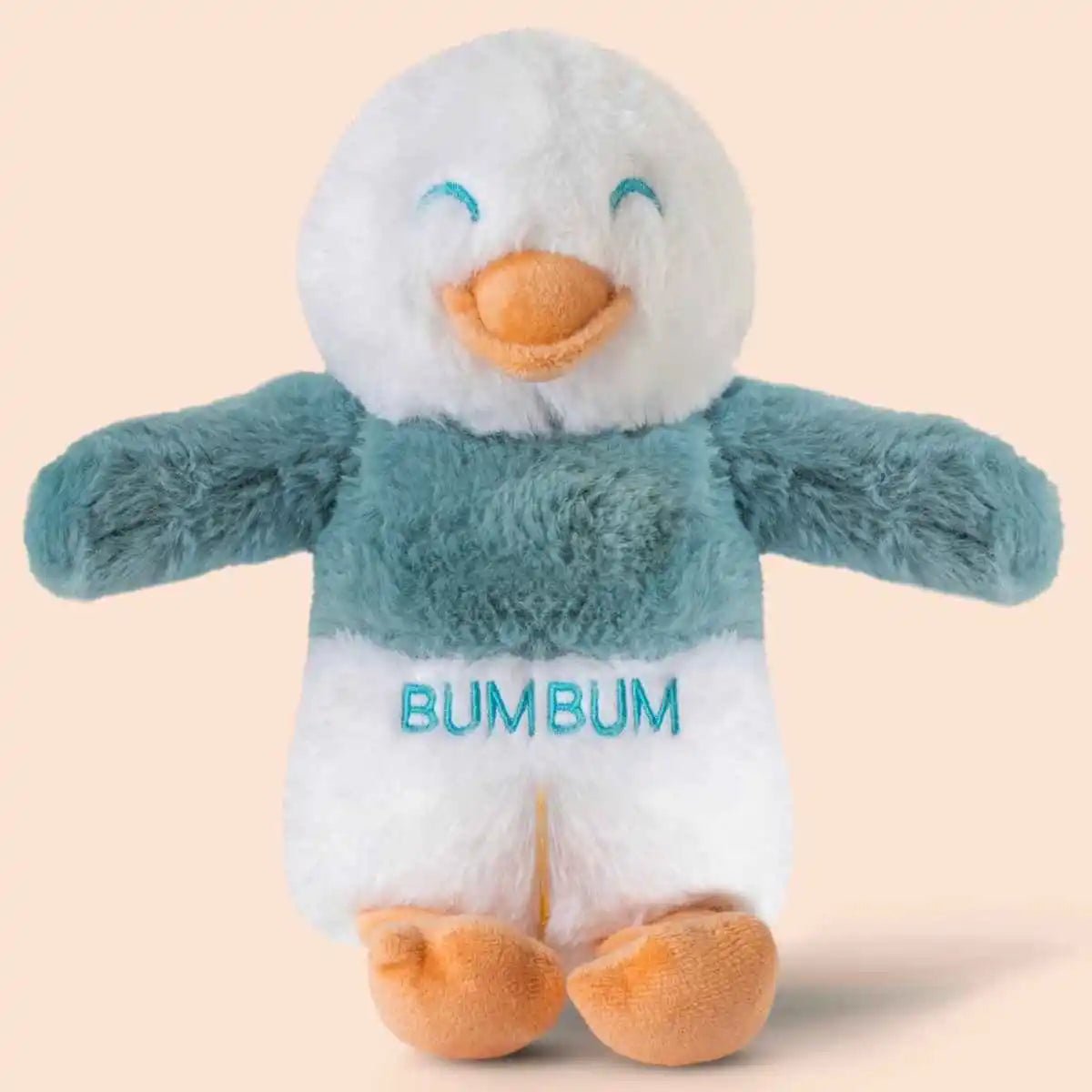 Plush toy penguin with 'BUMBUM' text on a beige background